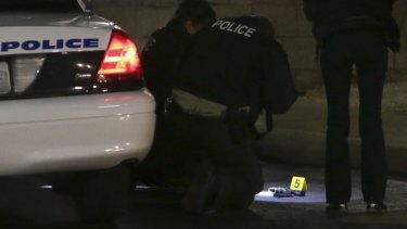 Police photograph a gun on the ground outside a gas station after a shooting.