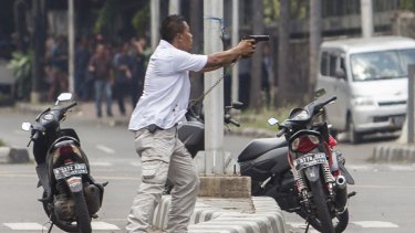 A plain-clothes police officer aims his gun at attackers during a gun battle following explosions in Jakarta.