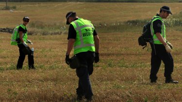 Australian Federal Police officers,  with their Malaysian and Dutch counterparts, search the MH17 crash site for human remains in August 2014