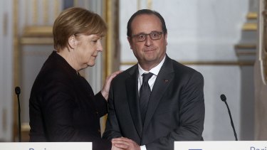 French President Francois Hollande shakes hands with German Chancellor Angela Merkel at the Elysee Presidential Palace in Paris  on Wednesday. Mr Hollande is seeking to establish a "grand and single coalition" to fight IS.