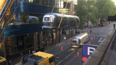 An Airstream trailer is craned on to the roof of Fry's Fast Park in Flinders Lane.