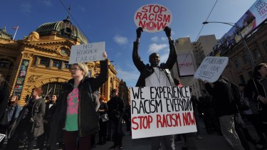 Demonstrators protesting against planned border protection raids stop traffic outside Flinders Street Station on Friday.