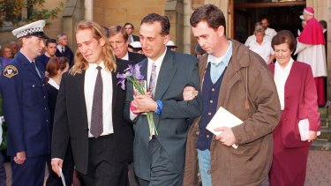 Walter Mikac is comforted by family and friends at the memorial service in May 1996 for the victims of the shooting in Tasmania.