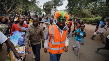 Supporters of Kenyan opposition leader Raila Odinga celebrate in Uhuru Park, Nairobi, one wearing a wig and mask with the acronym of Odinga's National Super Alliance (NASA).