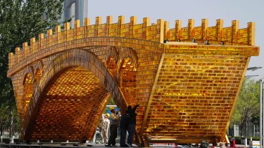 Workers install wires on a 'Golden Bridge of Silk Road' structure on a platform outside the National Convention Centre in Beijing.