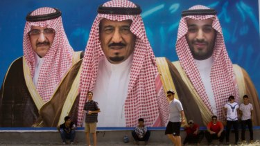 Saudi boys pose in front of a huge billboard showing in the centre, King Salman, with Mohammed bin Salman to the right, and the replaced Prince Mohammed bin Nayef, left, in Taif, Saudi Arabia. 