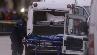 Two men carry a stretcher with a dead body into a hearse after the police raid in Saint-Denis, north Paris.