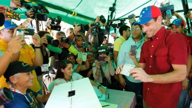 Opposition leader Henrique Capriles shows a ballot during a symbolic referendum in Caracas, on Sunday.