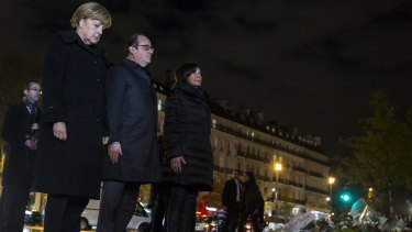 From left, German Chancellor Angela Merkel, French President Francois Hollande and Paris mayor Anne Hidalgo pay their respects to the victims of the Paris attacks at the Place de la Republique where they each left a white rose on Wednesday.
