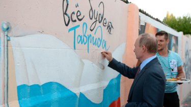 Russian President Vladimir Putin signs a mural of a Russian  flag and text reading 'All will be well. Tavrida', on a visit to Crimea in August.