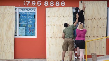 Local residents install wood panels over a storefront window in Carolina, Puerto Rico.