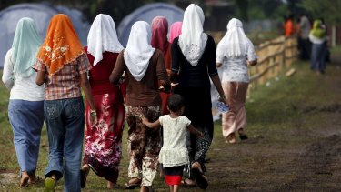 Rohingya migrants who arrived in Indonesia last week by boat walk back after collecting breakfast at a temporary shelter in Aceh Timur.