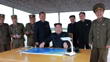 Kim Jong-un, centre, smiles at the site of the test launch of a Hwasong-12 intermediate range missile in Pyongyang on Tuesday in this photo distributed by the regime's news agency.