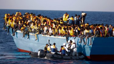 Italian officers rescue a woman from a crowded wooden boat carrying more than seven hundred migrants, during a rescue operation in the Mediterranean, off Libya last month. 
