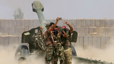 Fighters take a selfie while firing artillery against Islamic State militants in Fallujah, Iraq.