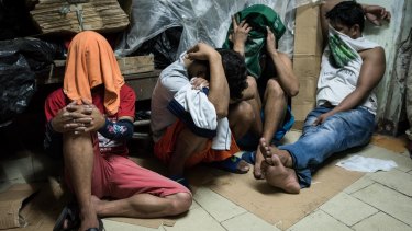 Alleged drug suspects cover their faces during a drug raid on December 9, 2016 in Manila, Philippines. 