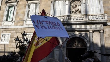 A man holds up a Spanish national flag outside the entrance to the regional Catalan government office in Barcelona, on Monday as Spain took control of it with little resistance from ousted officials.