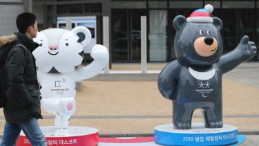 A man passes by official mascots of the 2018 Pyeongchang Winter Games, a white tiger "Soohorang" for the Olympic, and the Asiatic black bear "Bandabi" for the Paralympic, in downtown Seoul.