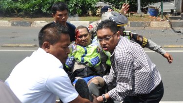 People carry an injured police officer near the site where an explosion went off at a police post in Jakarta.