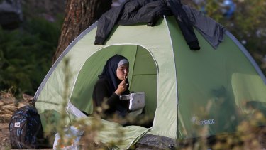 A migrant eats a meal as she sits in a tent near the border train station of Idomeni, northern Greece, as they wait to be allowed by the Macedonian police to cross the border from Greece to Macedonia on Thursday.