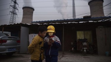 Chinese boys look at a smartphone in front of their house next to a coal fired power plant on the outskirts of Beijing earlier this week. 
