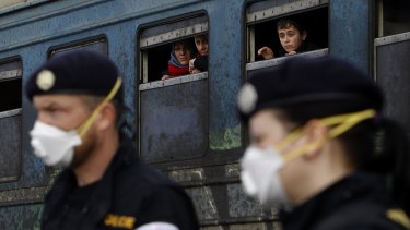 Refugees aboard a train bound for Serbia watch Czech Republic police officers maintaining order at the transit centre for refugees, near southern Macedonia's town of Gevgelija on Sunday. 