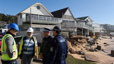 Warringah Council group manager of natural environments Todd Dickinson (left) and consultant Angus Gordon (second from left) speak with police during an inspection of damaged beachfront homes.