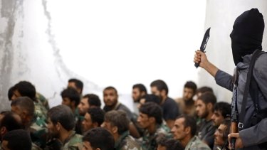 This undated photo posted in August 2014 by the Raqqa Media Centre of Islamic State shows a fighter from the group next to captured Syrian army soldiers and officers, following the battle for the Tabqa air base.