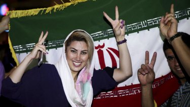 An Iranian woman shows the victory sign as people celebrate on the streets of Tehran following the landmark nuclear deal.