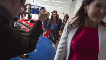 Paul Oei photographs his wife Loretta Lai, centre, with a new car at a Lamborghini dealership reception in Vancouver.