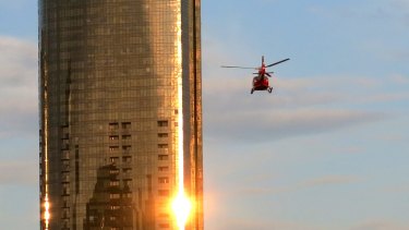 A helicopter flies through Melbourne skyscrapers along the Yarra River.