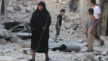 Civilians walk on rubble as they inspect a site hit by what activists said was a barrel bomb dropped by forces loyal to Syria's President Bashar al-Assad in the old city of Aleppo on July 12.