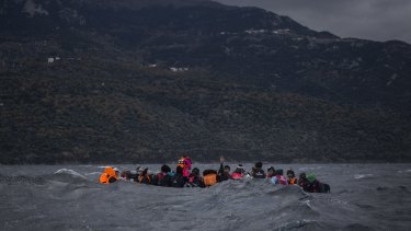 Refugees on a dinghy approach the Greek island of Lesbos. 13 people have drowned after their boat overturned in rough seas on Wednesday.