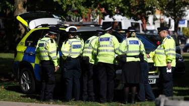 Police and community support officers gather round a police vehicle near where the incident happened.