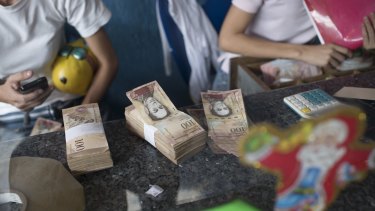 Employees organise 100-bolivar notes at a lottery store in Caracas, Venezuela, on Monday.