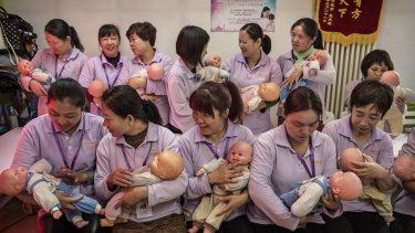 Chinese women hold plastic babies at the Ayi University which teaches childcare, early education in preparation for higher demand for domestic services.