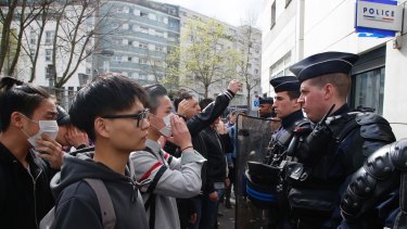 Demonstrators from the Asian community face riot police officers outside Paris' 19th district police station on Tuesday.