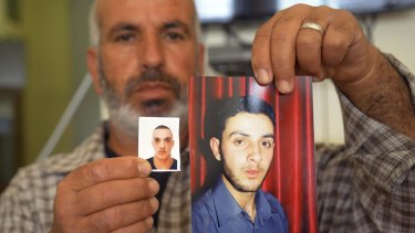 A relative with photos of the Har Nof synagogue attackers, Ghassan (right) and Uday Abu Jamal, outside the family home in Jerusalem.