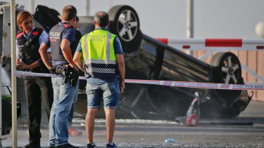 Police officers stand near an overturned car at the spot where terrorists were intercepted by police in Cambrils on Friday.