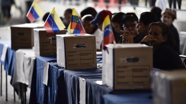 Polling officials wait for voters during the symbolic Venezuelan plebiscite in Caracas called by opposition parties.