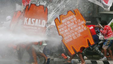 A fireman trains his hose on protesters as they force their way towards the US embassy in Manila on Wednesday.