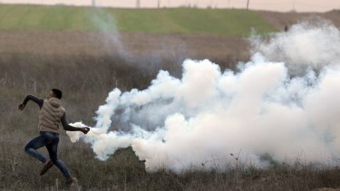 A Palestinian protester throws back a teargas canister fired by Israeli troops during clashes on the Israeli border with Gaza, on Sunday