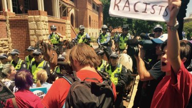 Police hold back anti-racist protesters at Parliament House.