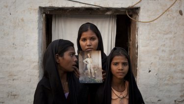 Fate altered: The daughters of Asia Bibi, pictured here in 2010, pose with an image of their mother.