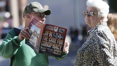 A newsagent shows a passerby a magazine in Dealey Plaza Dallas, on Wednesday.