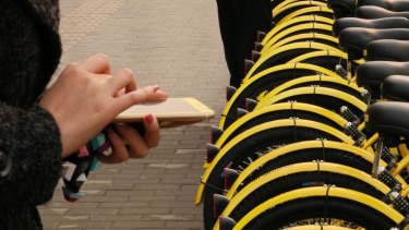 A young commuter unlocks a share bike in Beijing's CBD using her smartphone.
