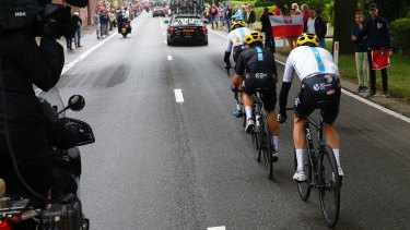 Chris Froome, his skin suit torn after crashing, is paced back to the peloton by his Team Sky teammates.