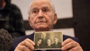 Auschwitz concentration camp survivor Leon Schwarzbaum presents an old photograph showing himself, left, next to his uncle and parents who all died in Auschwitz during a press conference in Detmold, Germany.