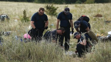 Australian Federal Police officers and their Dutch counterparts collect human remains from the MH17 crash site. 