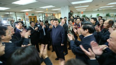 Workers applaud as Chinese President Xi Jinping talks with staff at the People's Daily in February.